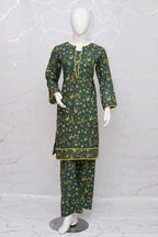 A dark green three-piece kurta set with a yellow floral pattern, displayed on a white mannequin against a light marble-patterned wall.